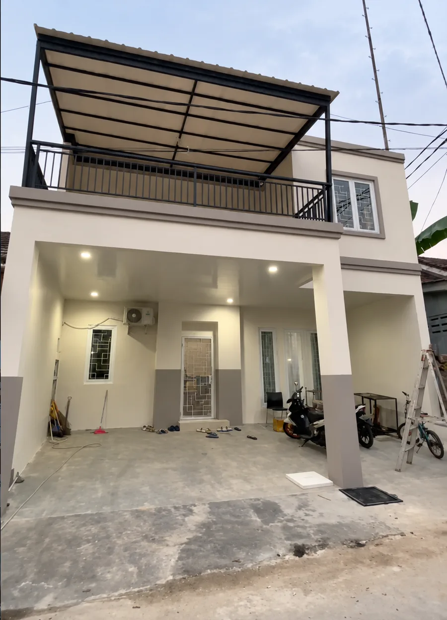 Rumah dua lantai dengan teras, balkon, dan kanopi.